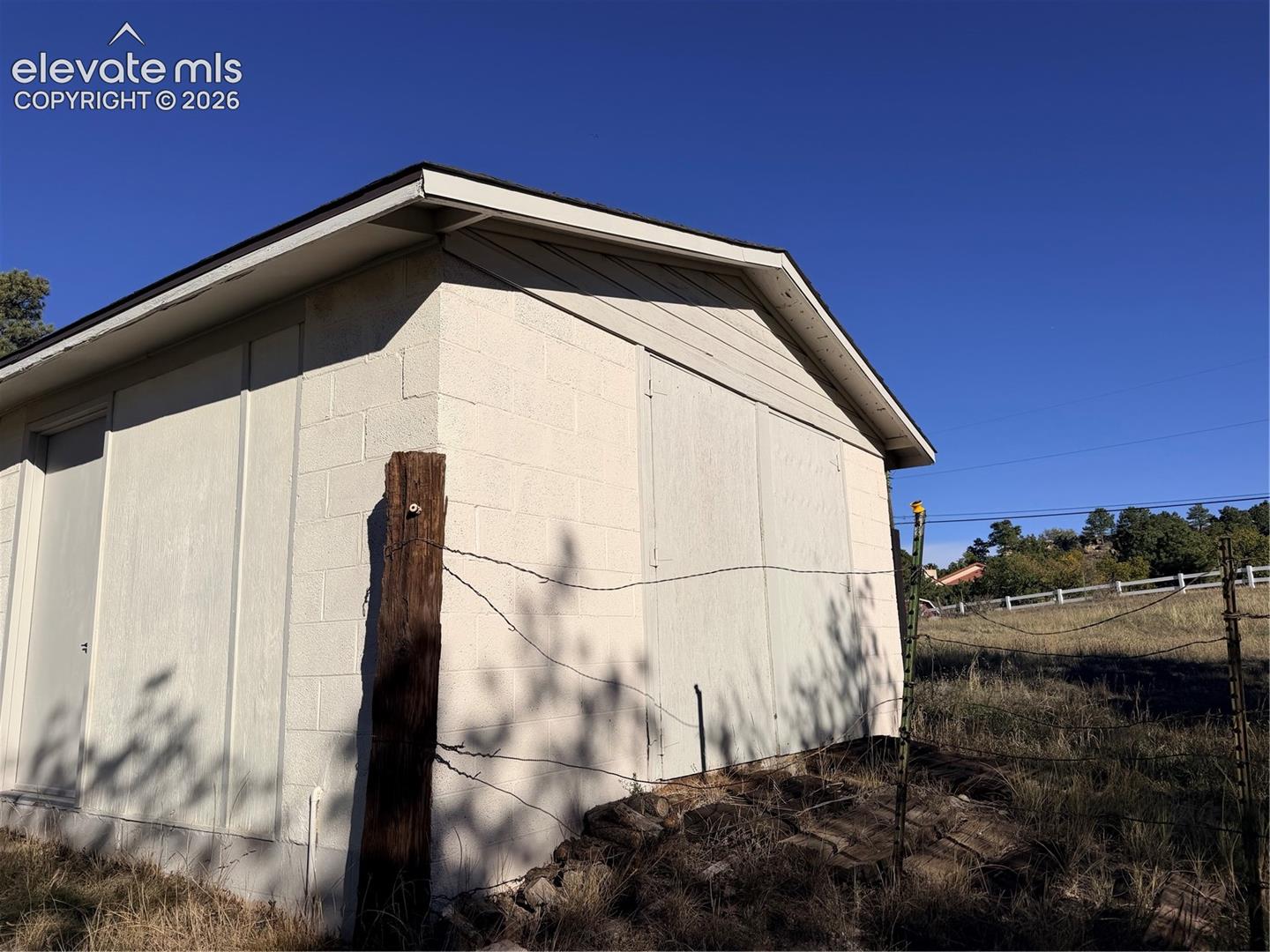 Exterior structure featuring painted concrete block walls and wood-finish siding under a gabled roofline