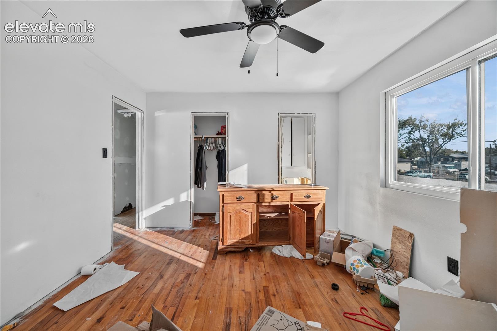 Wood-finish flooring, ceiling fan with integrated lighting, and large window