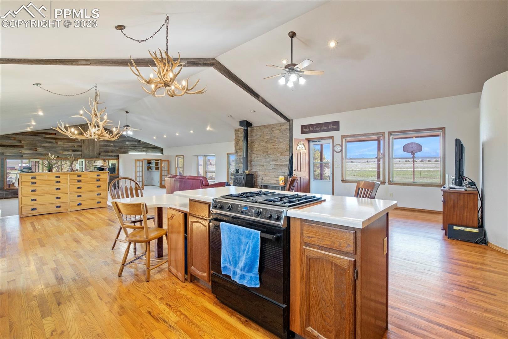 Open-concept kitchen featuring a center island with integrated range, white countertops, and wood cabinetry