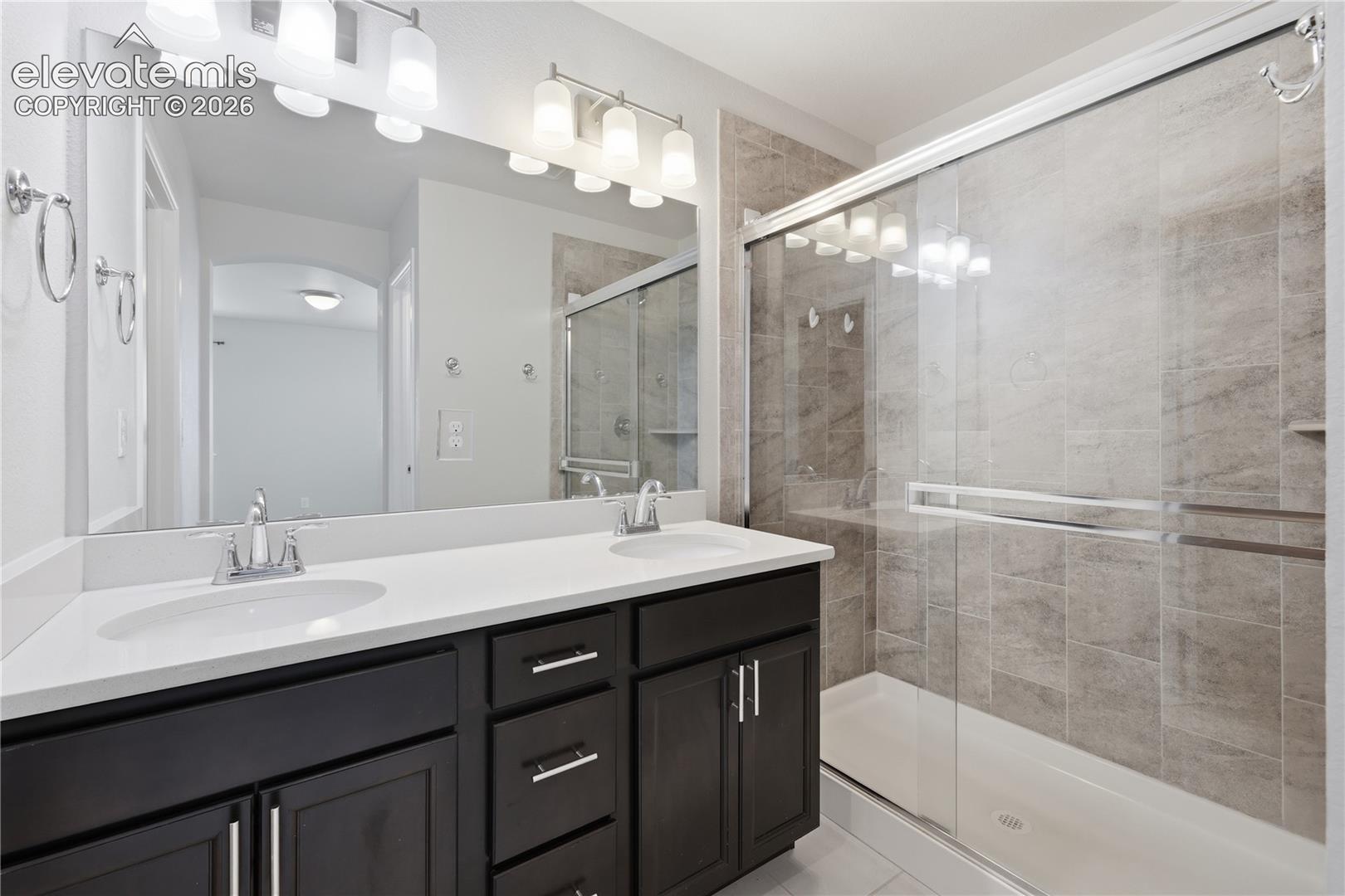 Primary Bathroom featuring a spacious double vanity with dark wood cabinetry, white countertops, and dual undermount sinks