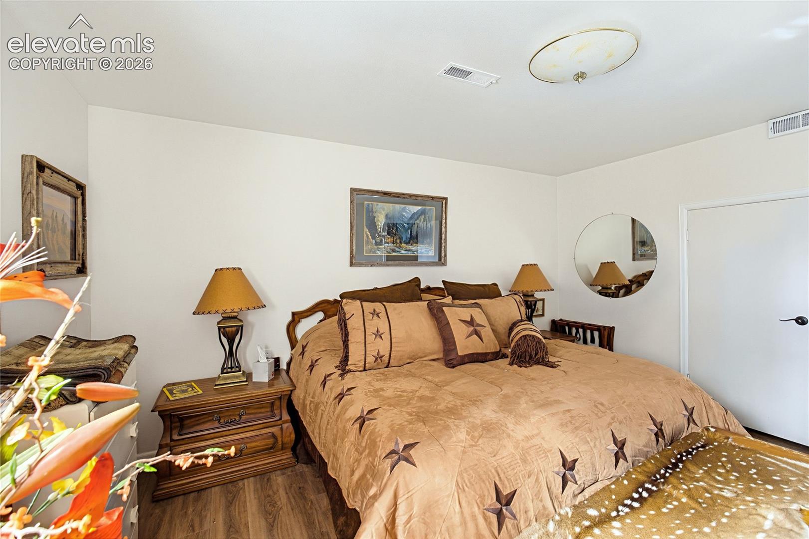 Bedroom space featuring wood-finish flooring and a flush-mount circular ceiling fixture
