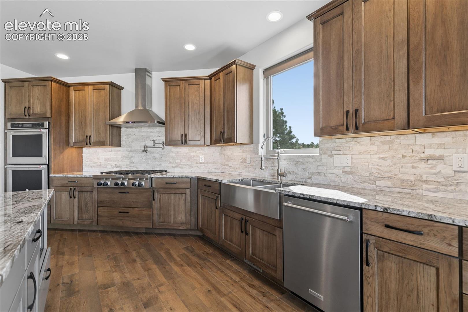 Wood-finish cabinetry complemented by light-toned stacked stone backsplash