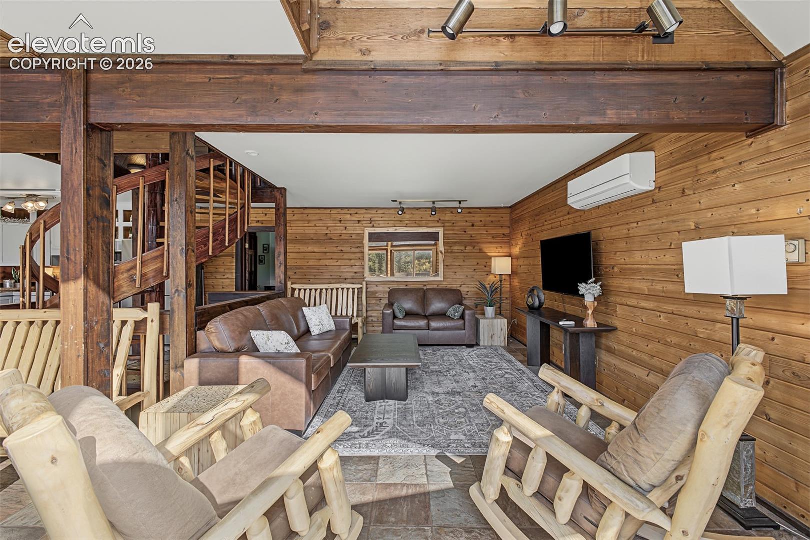 Wood-paneled living area featuring exposed wood beams and a spiral staircase