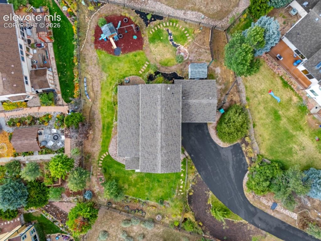 Extensive property featuring a shingle roof, asphalt driveway, multiple landscaped garden areas, and a detached shed