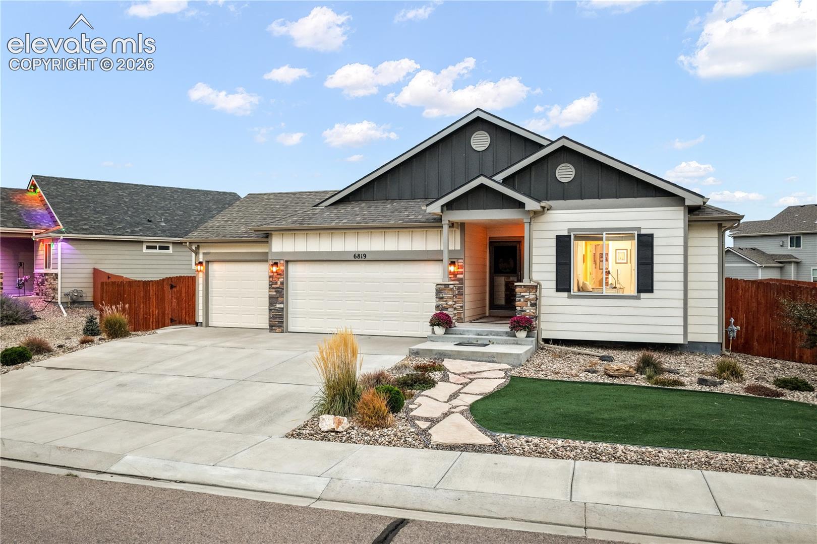 Exterior featuring a stone-accented facade, attached two-car garage, concrete driveway, and a flagstone pathway leading to the entry