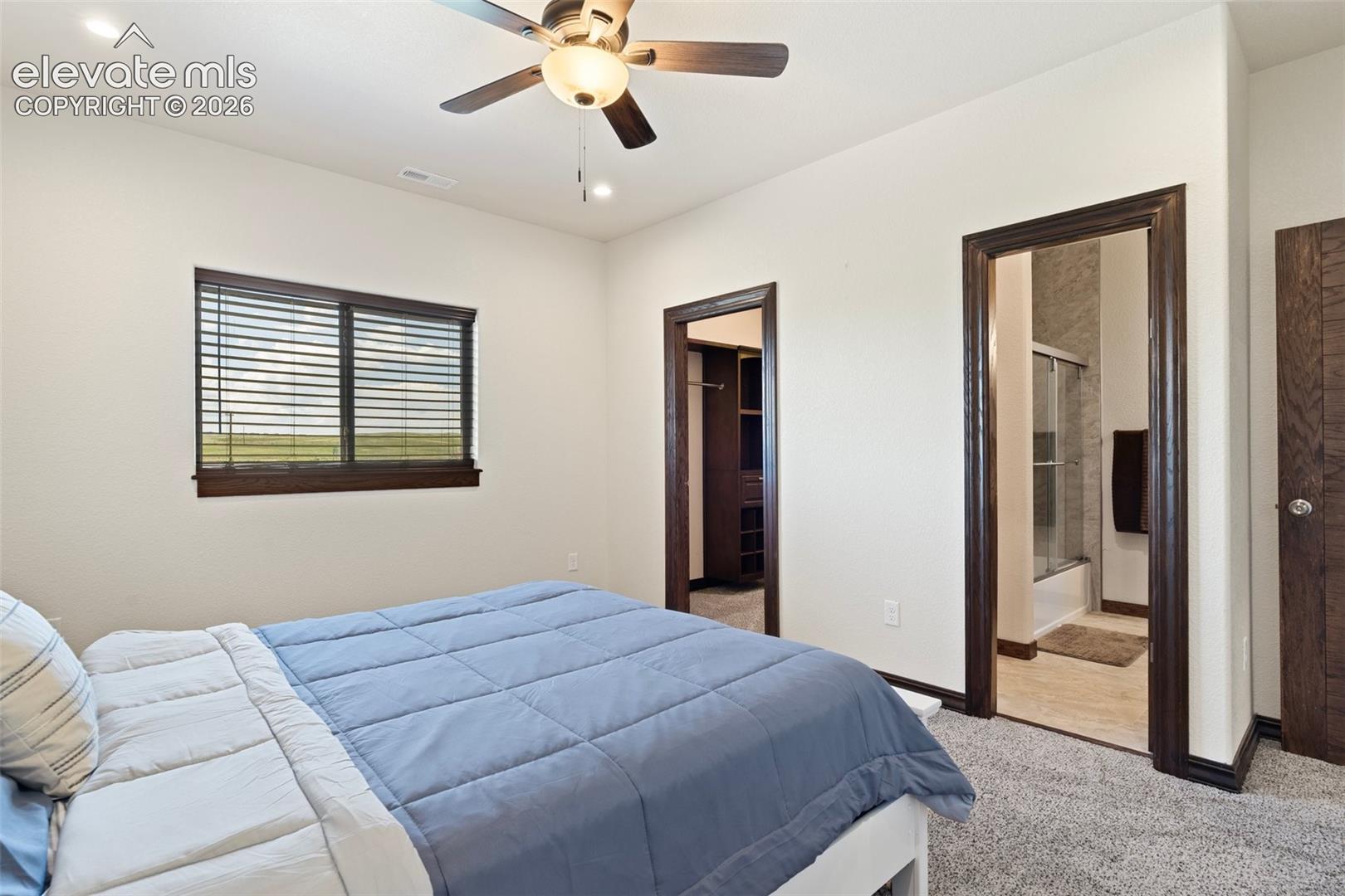 Bedroom featuring neutral wall tones, dark wood-finish trim, a ceiling fan with integrated lighting, and carpet flooring