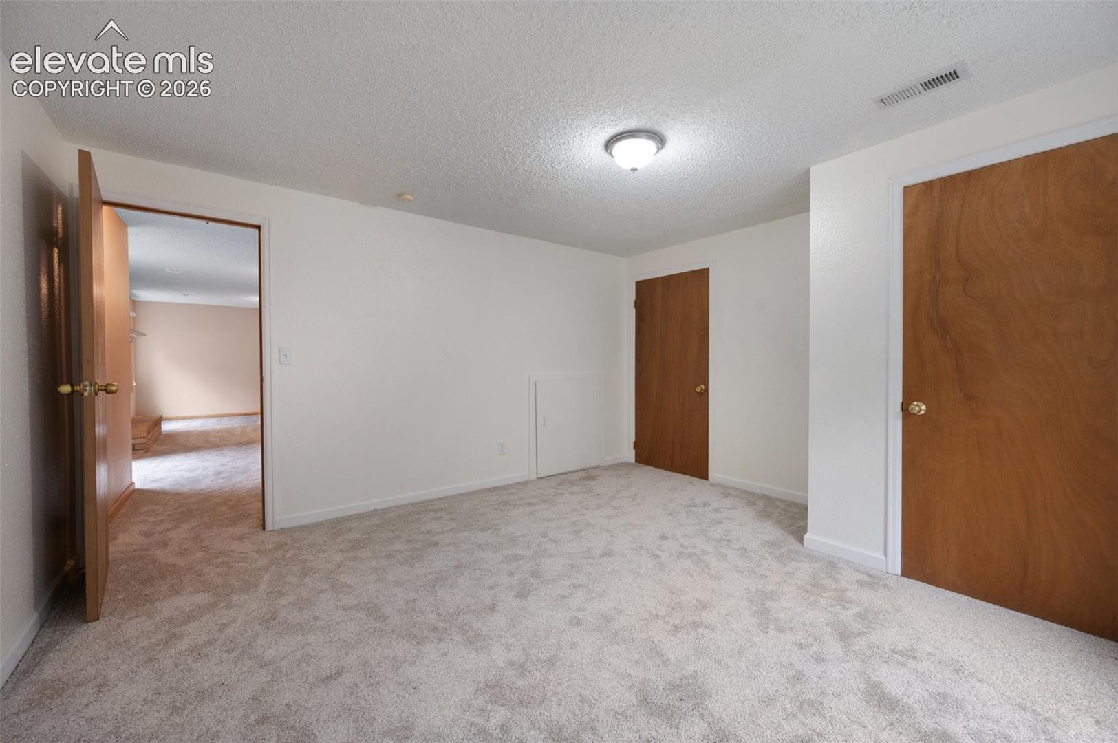 Unfurnished bedroom featuring carpet flooring, a textured ceiling, and baseboards