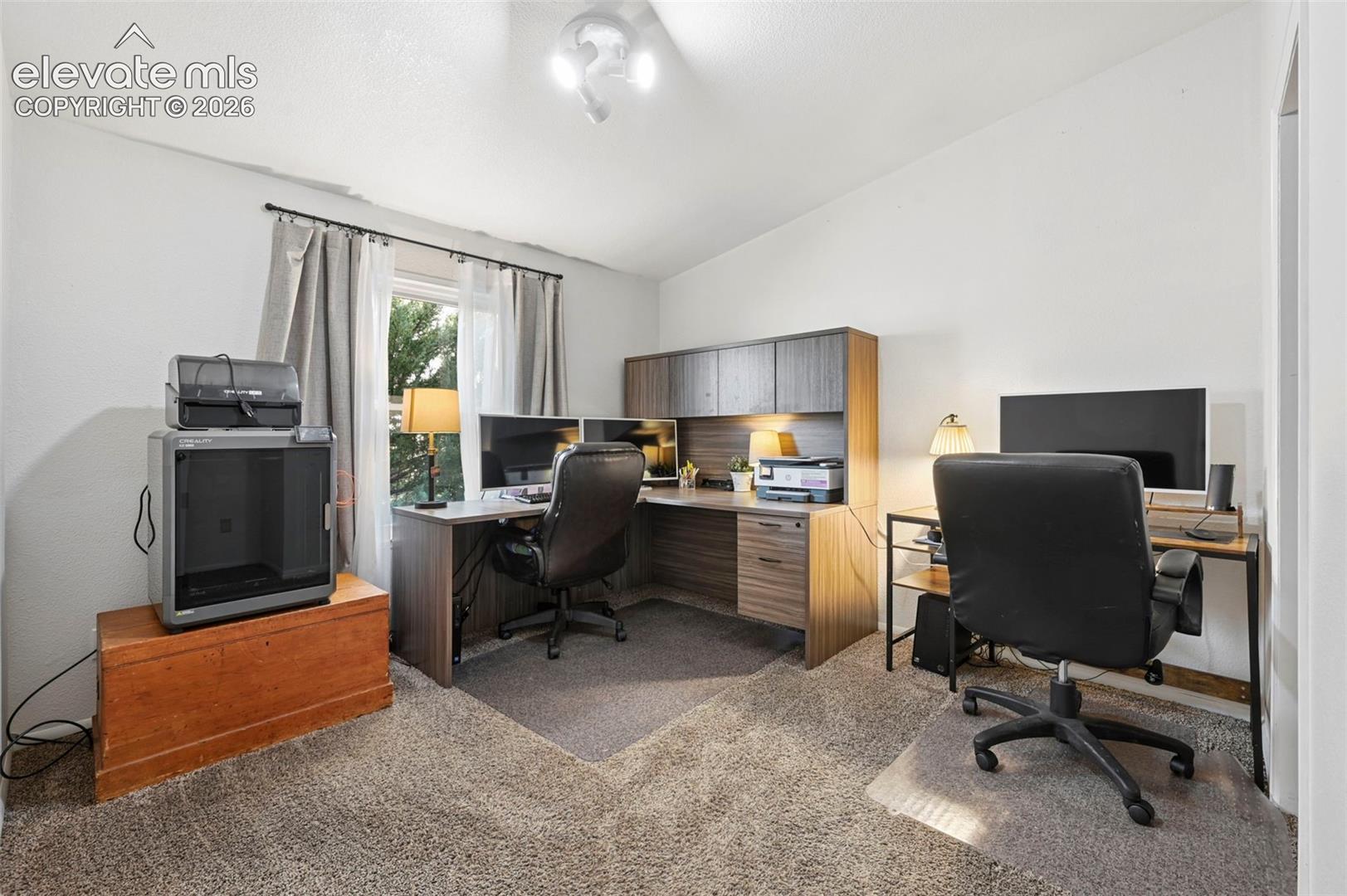 Built-in wood-finish workstation with overhead cabinetry and neutral wall-to-wall carpeting