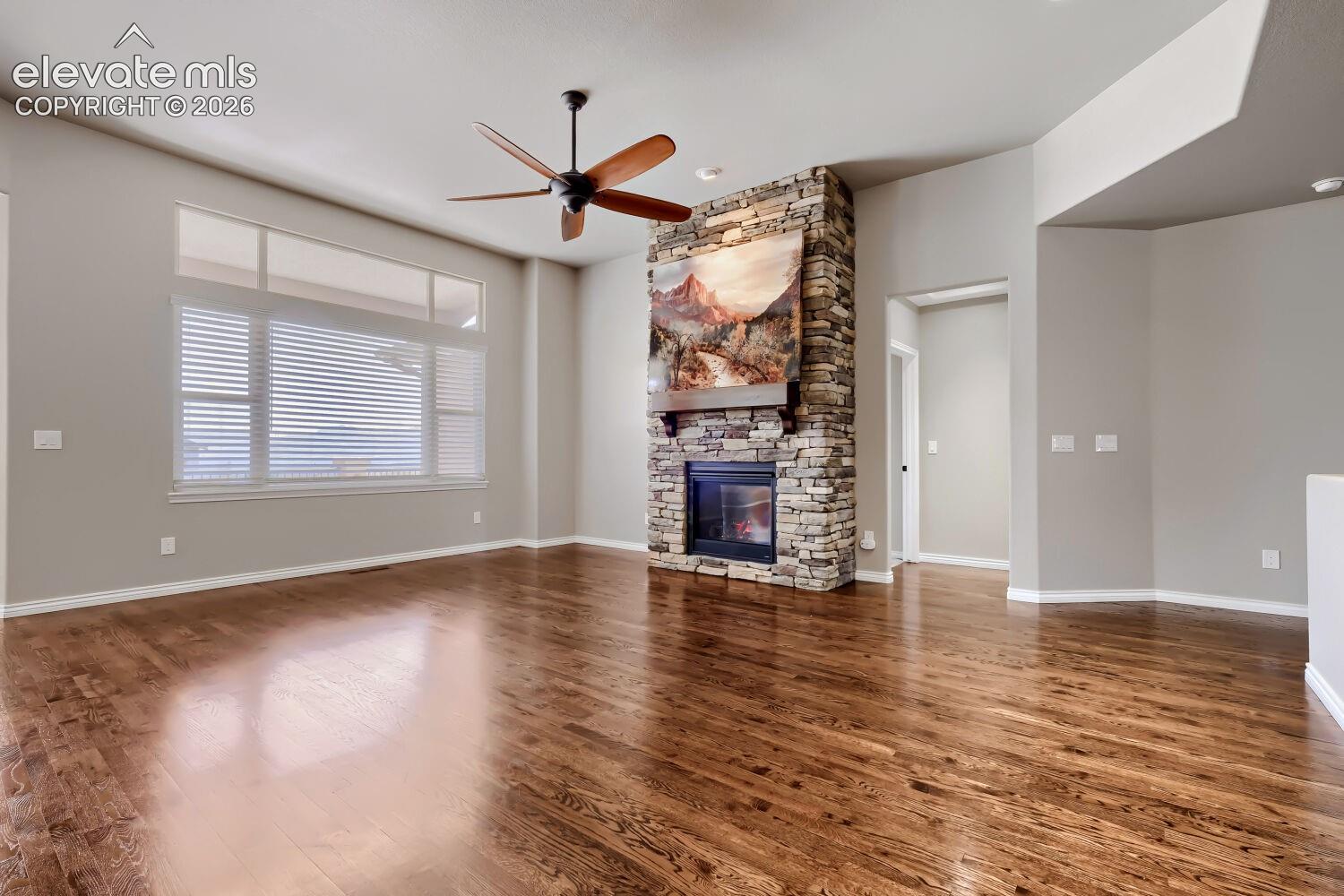 Living room with picture windows, stone fireplace, open concept design, gorgeous wood floors.