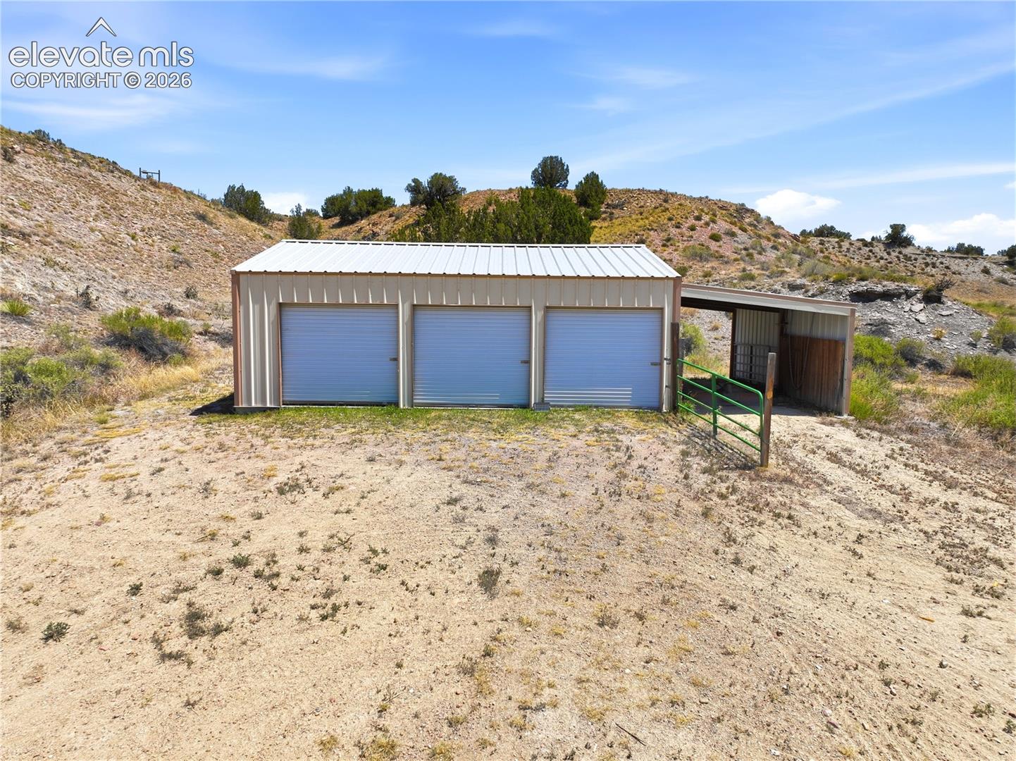 Steel-clad outbuilding featuring three roll-up doors and an attached covered lean-to