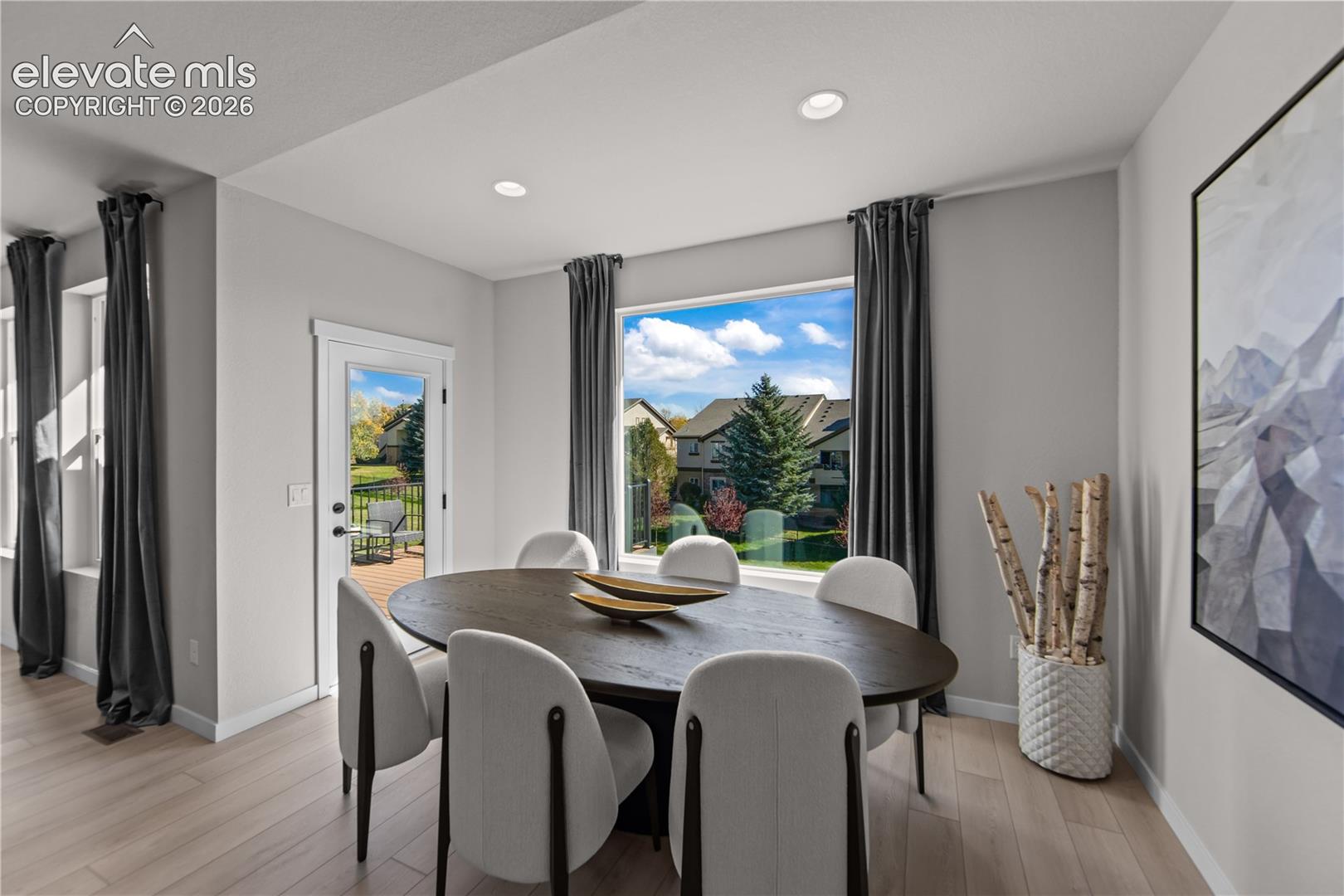 Dining area featuring light-toned wood-finish flooring, a large picture window, and a glass-paneled exterior door