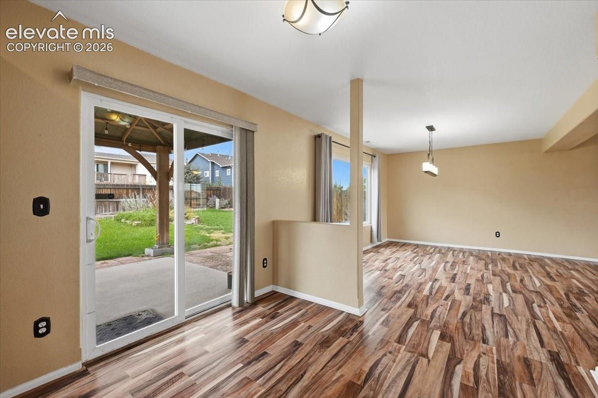 Wood-finish flooring, sliding glass door, recessed lighting, and a contemporary pendant light fixture