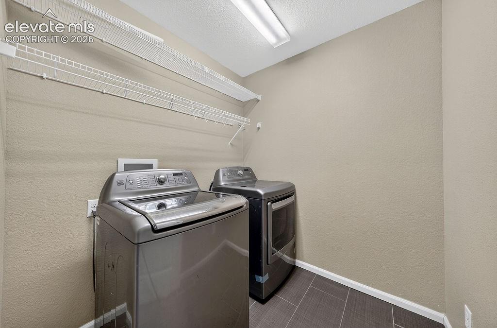 Dedicated laundry area featuring tile flooring and wire shelving