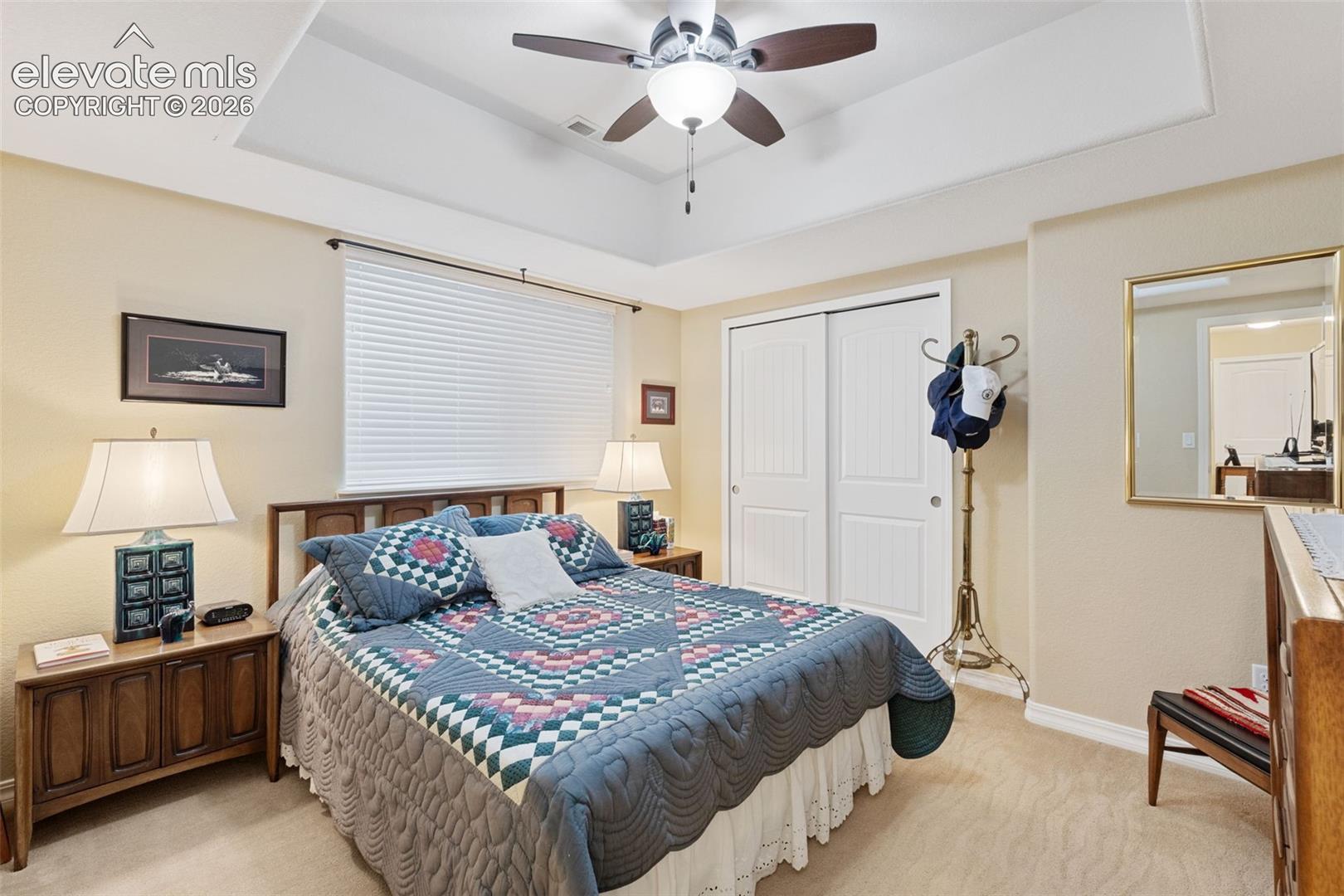 Carpeted bedroom with a ceiling fan, recessed lighting, and an entryway to a bathroom featuring a wood-finish vanity with a countertop