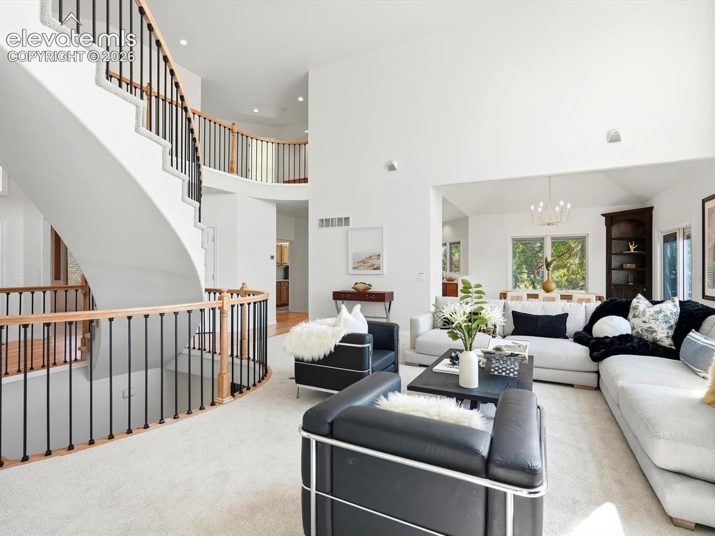 Curved staircase featuring wood handrails and black metal balusters, soaring vaulted ceilings, and built-in shelving