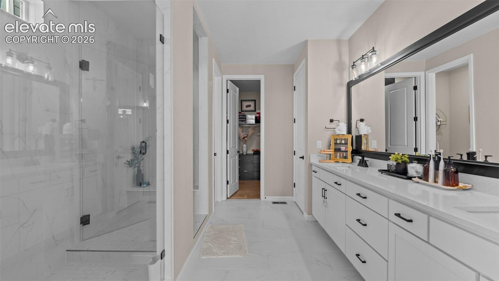 Dual vanity with white cabinetry, matte black hardware, and an expansive mirror