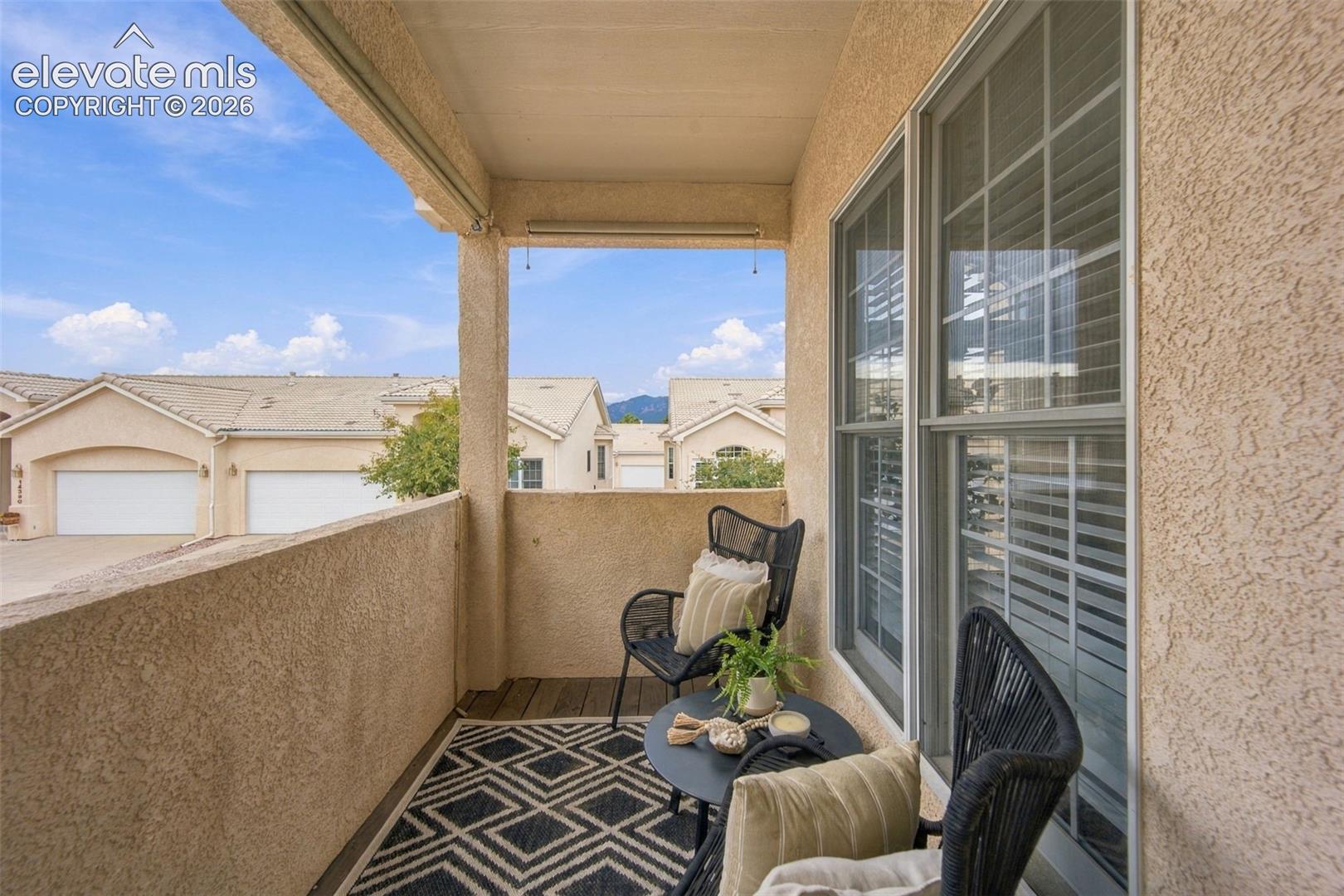 Covered balcony featuring textured stucco walls, wood-finish flooring, and mountain backdrop