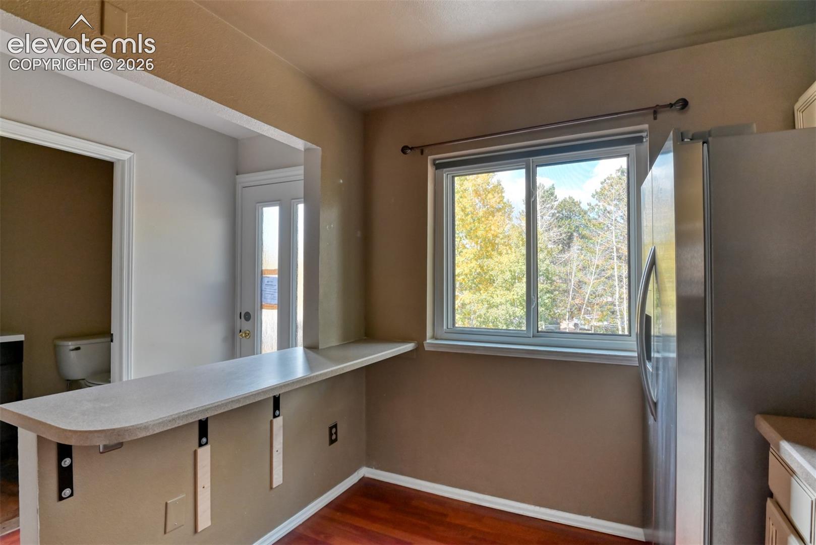 Built-in counter with support brackets, wood-finish flooring, and a large window