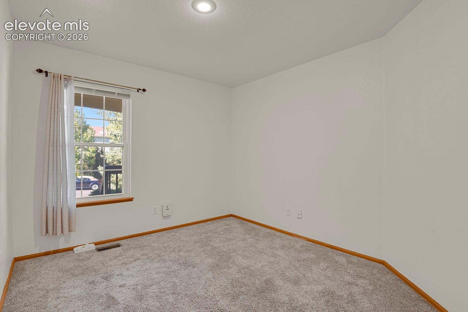 Recessed ceiling light, neutral wall paint, single window, wood-finish trim, and carpeted flooring