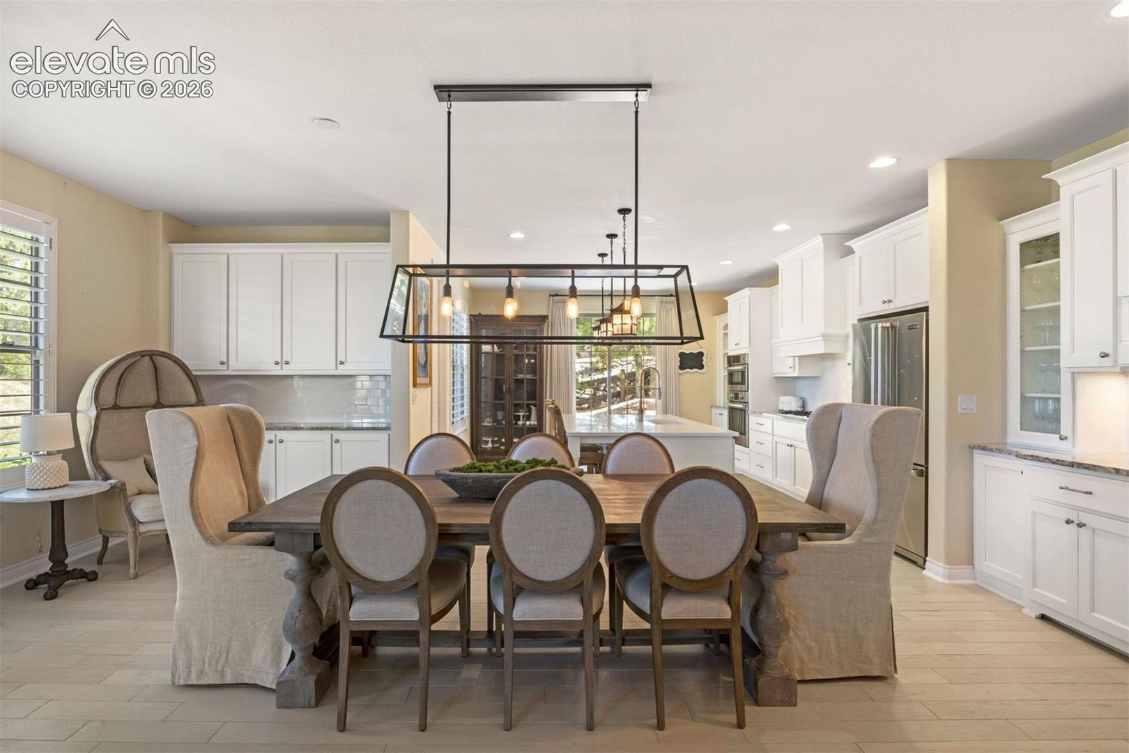 Open-concept dining area featuring light-toned flooring, a linear chandelier, and recessed lighting