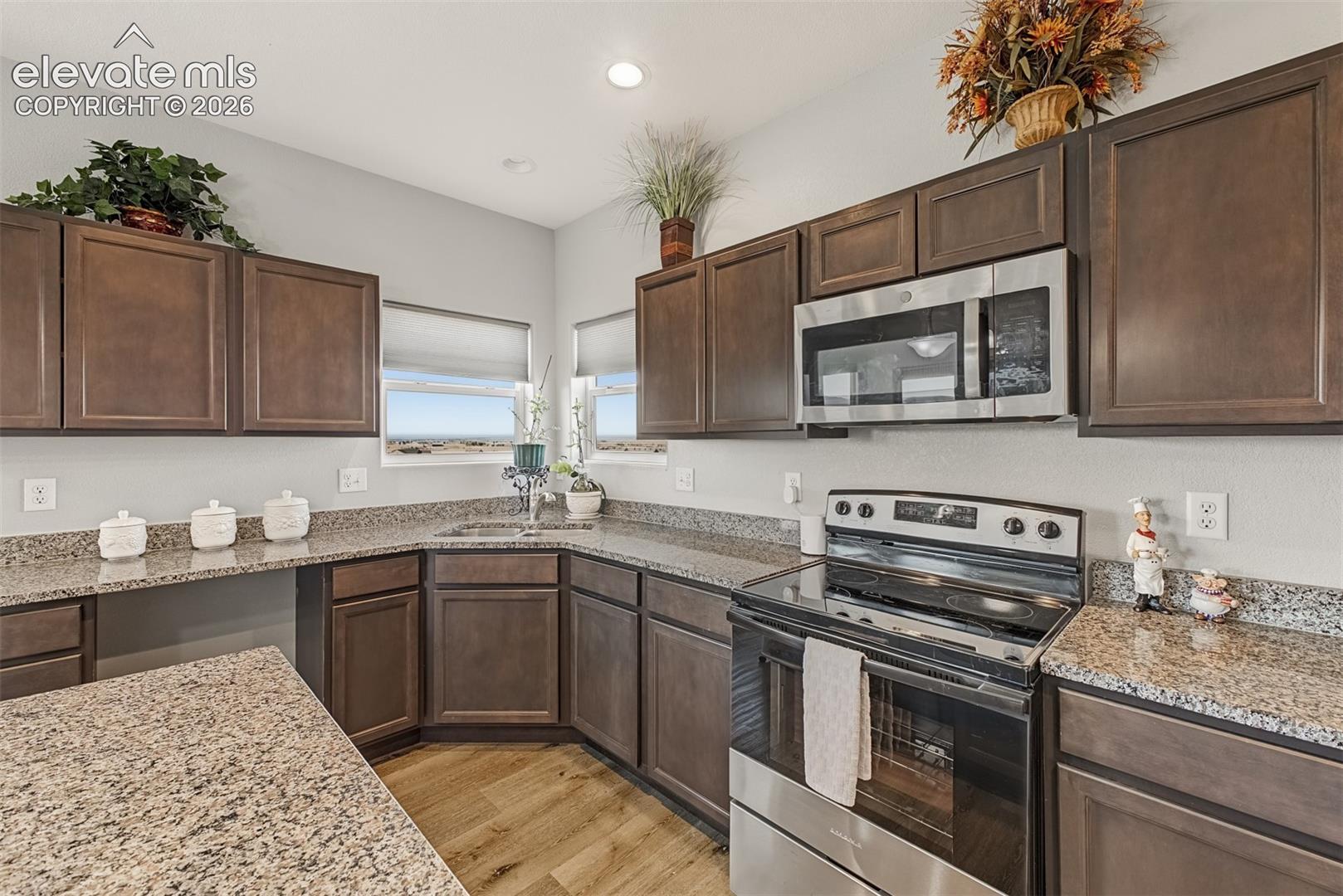 Kitchen featuring dark-finish cabinetry, granite countertops, stainless steel appliances and plenty of accent lighting.