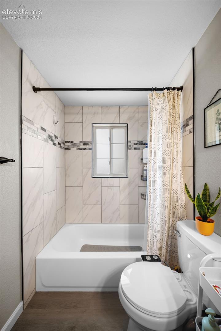 Bathtub with white subway tile surround, decorative mosaic accent tile, and a built-in window