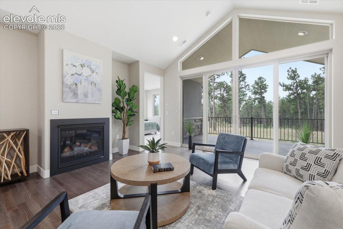 Vaulted Living Room with Gas Fireplace, Wood Flooring, and Oversized Double Sliding Doors.