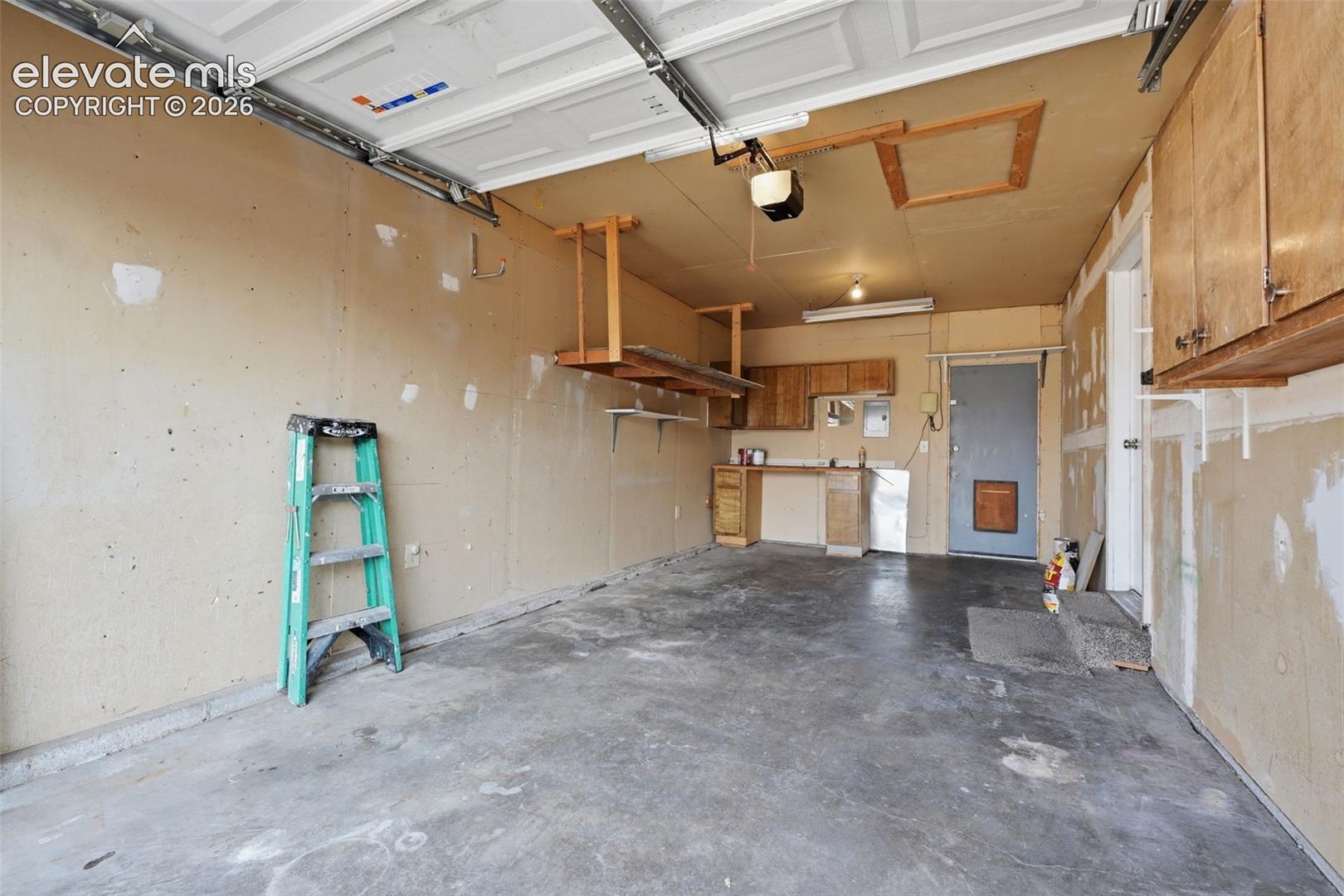 Garage space featuring built-in cabinetry, a utility sink, overhead shelving, and a concrete floor