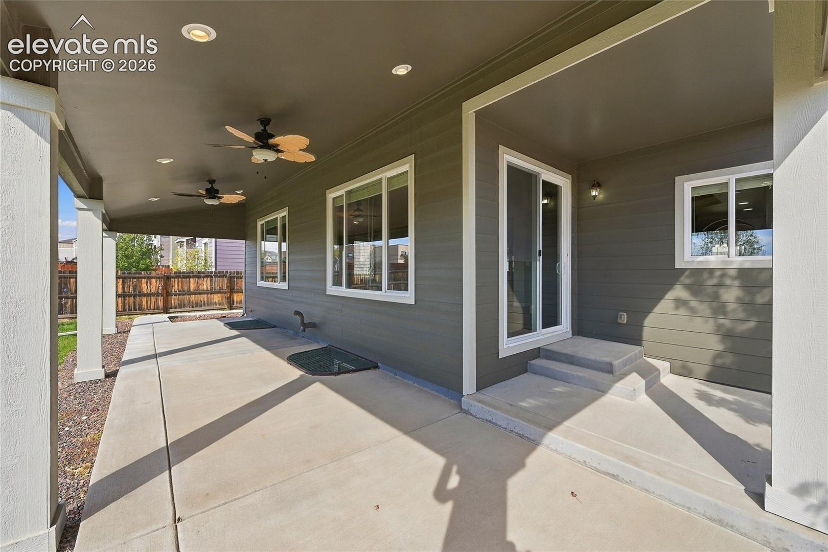 Covered concrete patio featuring recessed lighting, dual ceiling fans, horizontal siding, and sliding glass door entry