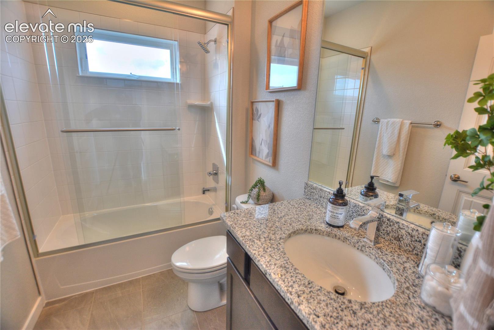 Contemporary bathroom featuring a granite-topped vanity with an undermount sink, large framed mirror, and brushed nickel fixtures