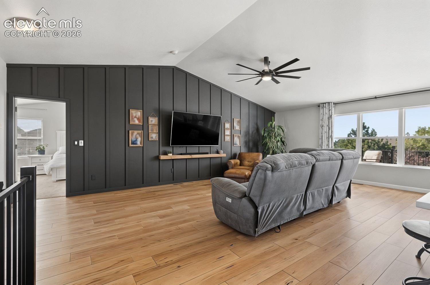 Spacious living area featuring luxury vinyl flooring, a contemporary ceiling fan, and multiple windows
