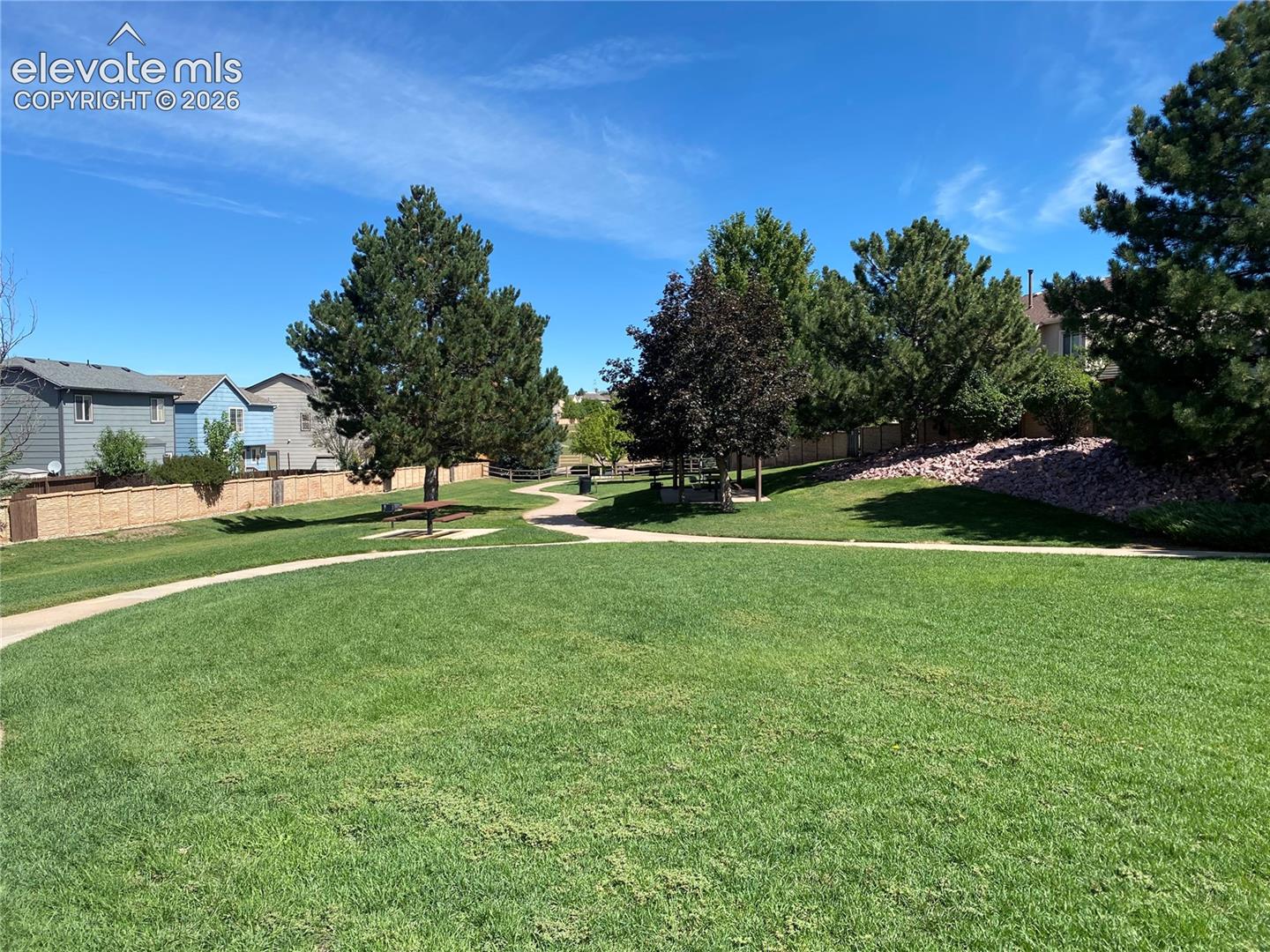 Grassy area on other side of the basketball/tennis court, with walking paths in view, and picnic tables/grill areas where residents can enjoy sun and fun.