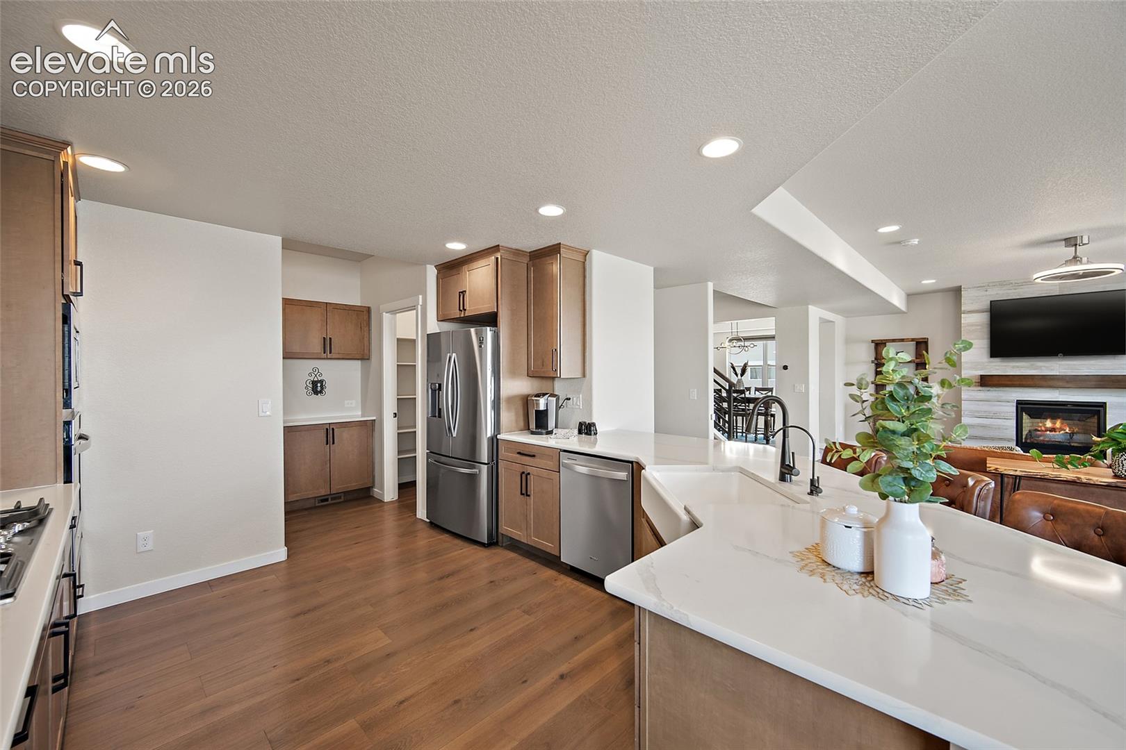 Kitchen featuring wood-finish flooring, recessed lighting, wood cabinetry, stainless steel appliances, and a kitchen island with a single-basin sink