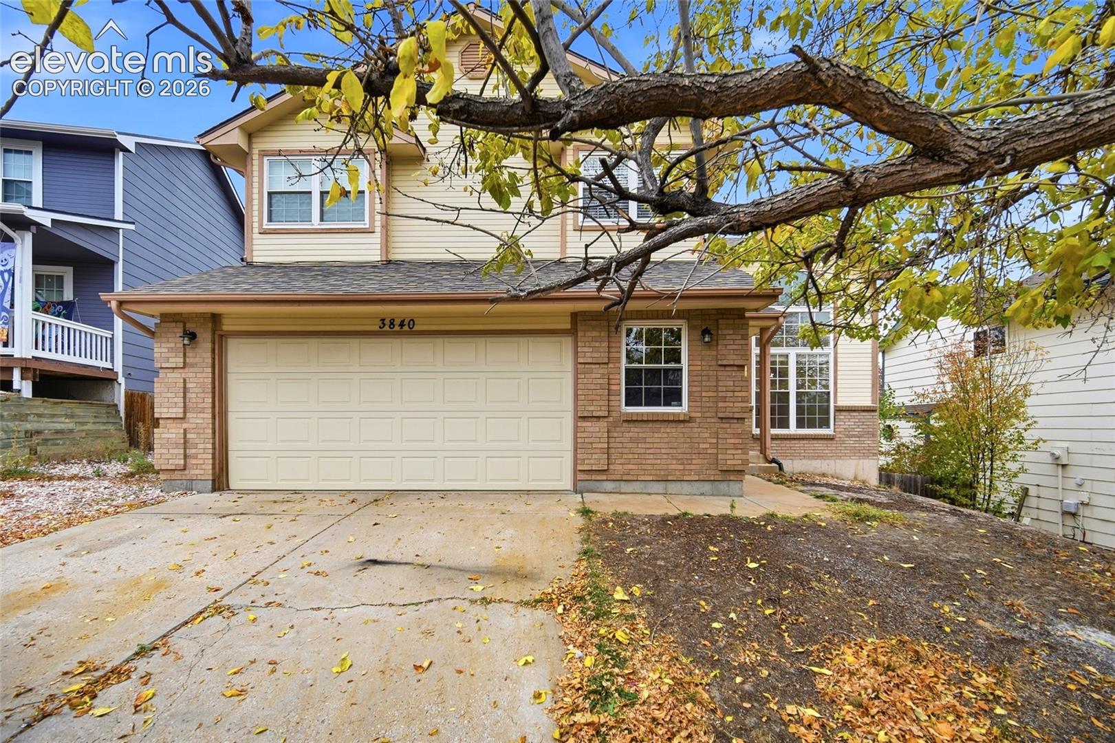 Two-story residence featuring a mixed-material exterior of horizontal siding and brick masonry, an attached two-car garage, and multi-pane windows