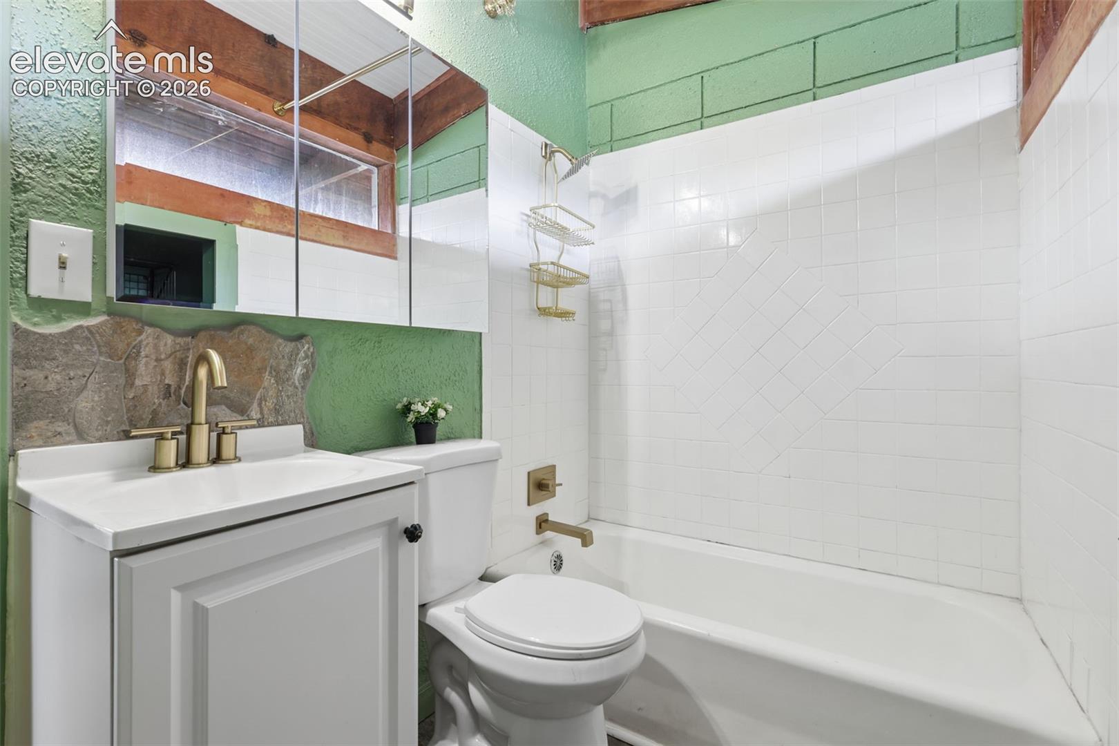 White vanity with integrated sink, brass-finish faucet, and a wall-mounted mirrored medicine cabinet