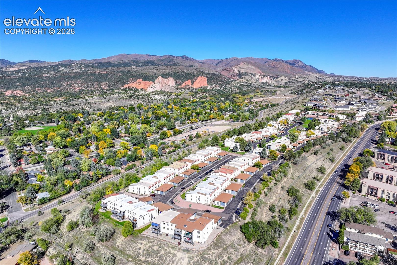 Aerial perspective of multi-unit residential buildings featuring asphalt parking, paved driveways, and expansive mountain backdrops