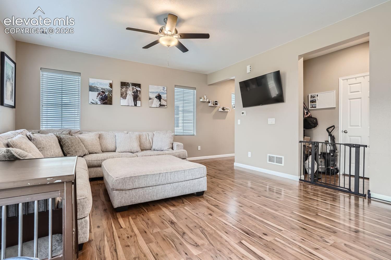 Living area featuring wood-finish flooring, recessed lighting, and a ceiling fan with integrated light fixture