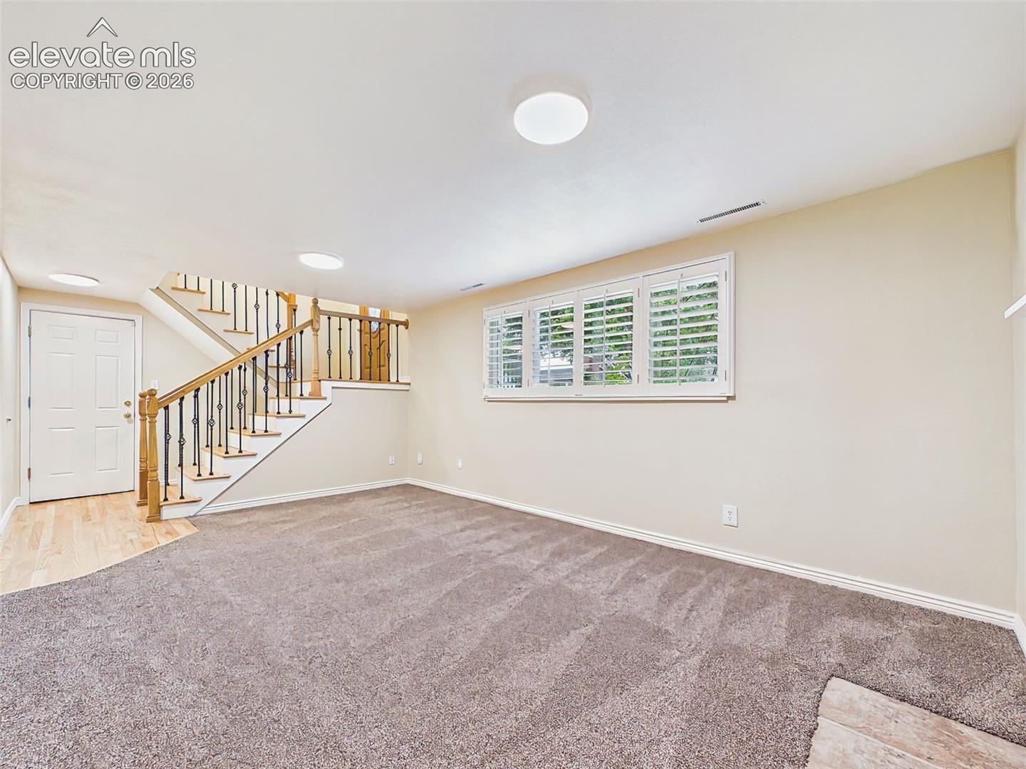 Family Room – Unfurnished view emphasizes the spacious layout, large picture window with plantation shutters, and flexible furniture placement options.