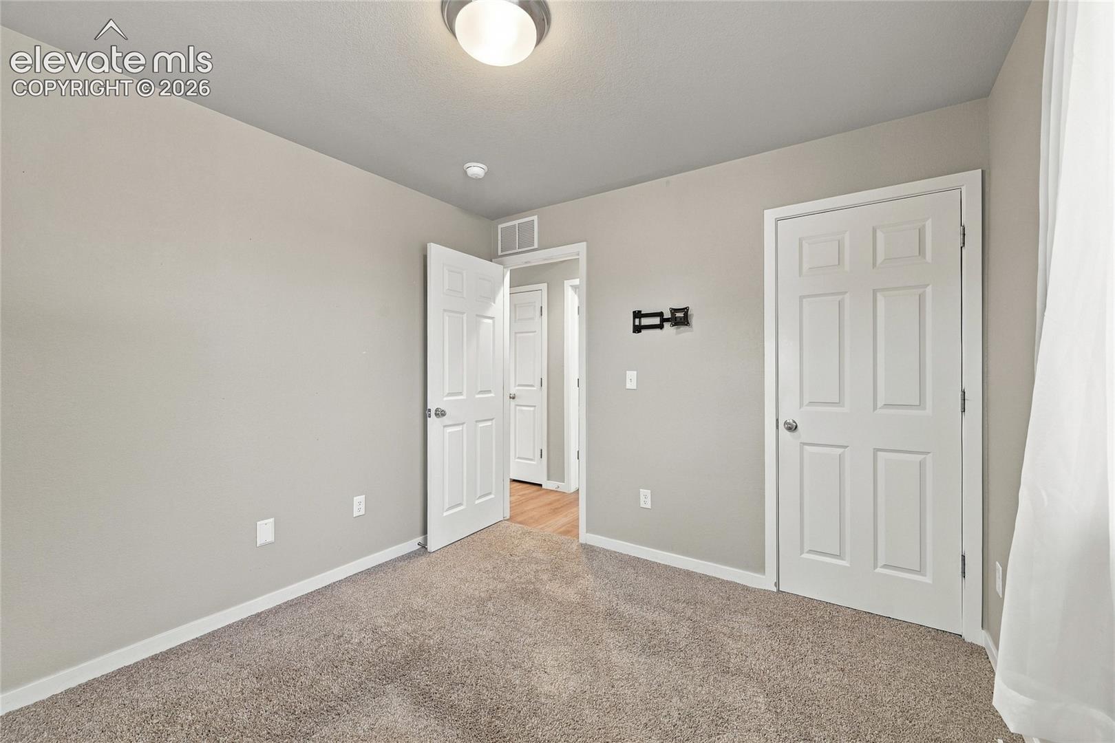 Neutral wall paint, carpeted flooring, white trim, paneled doors