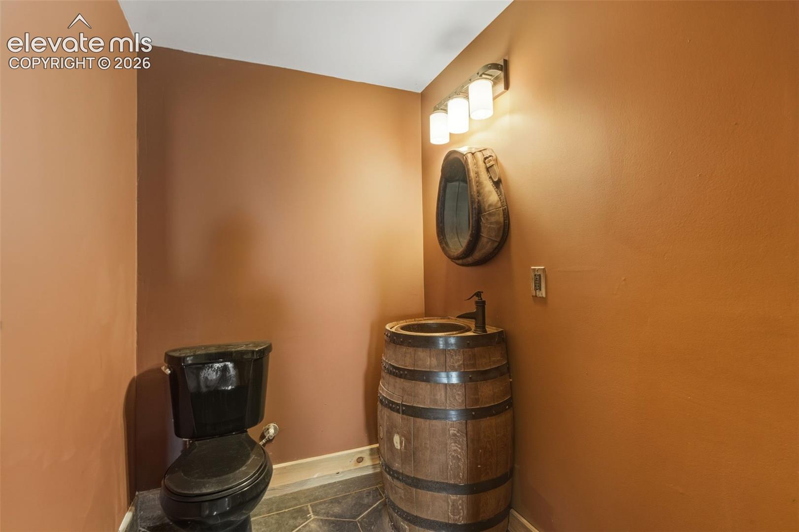 Barrel vanity with a vessel sink, black faucet, and coordinating black toilet