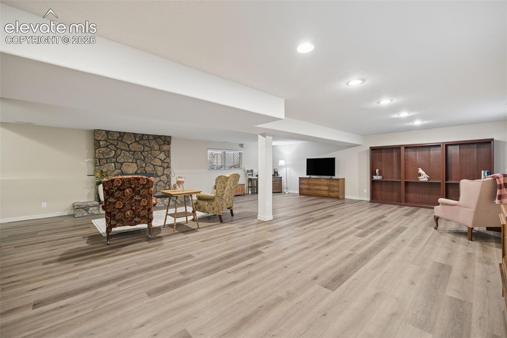 Spacious basement flex room with gas fireplace with stone surround and LVP flooring