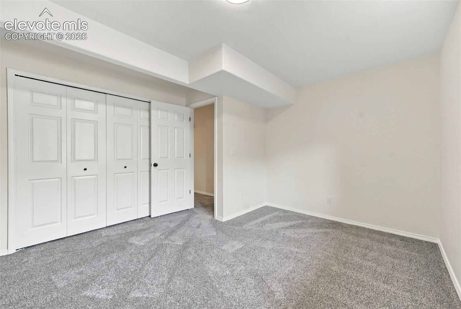 Neutral-toned interior space featuring plush wall-to-wall carpeting and a multi-panel bi-fold closet door