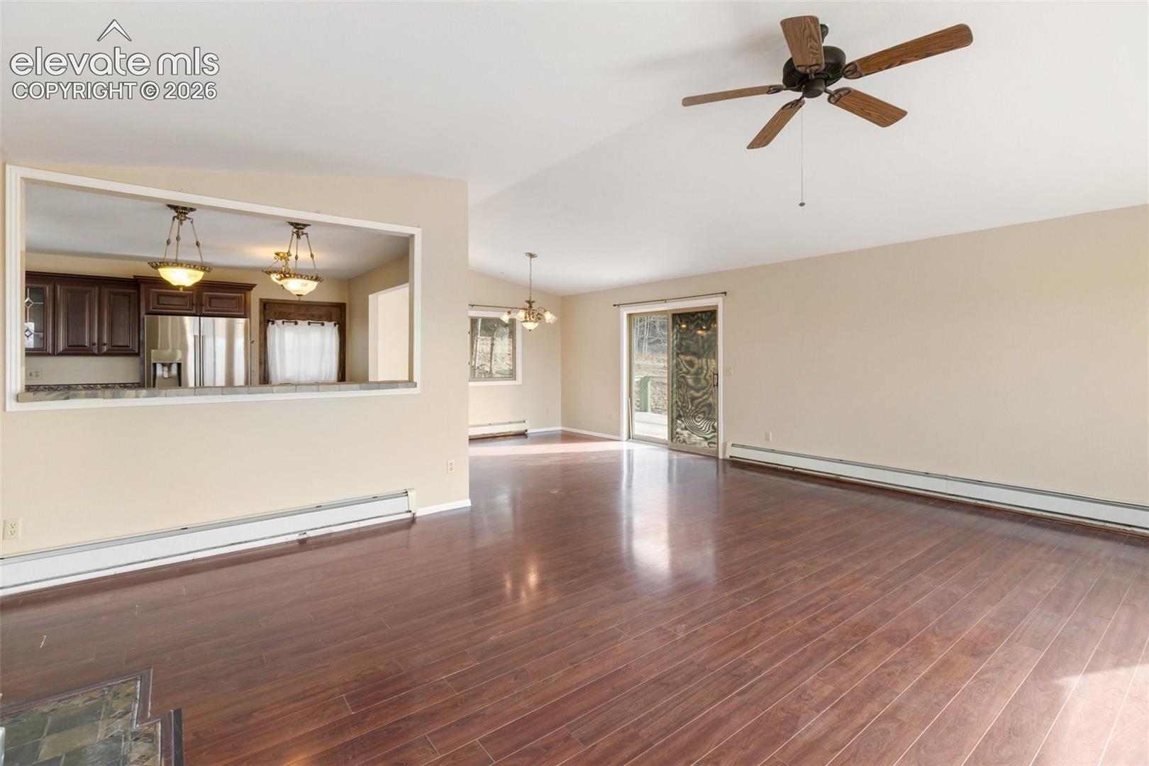 Expansive open-concept living area featuring wood-finish flooring, a ceiling fan, and sliding glass doors
