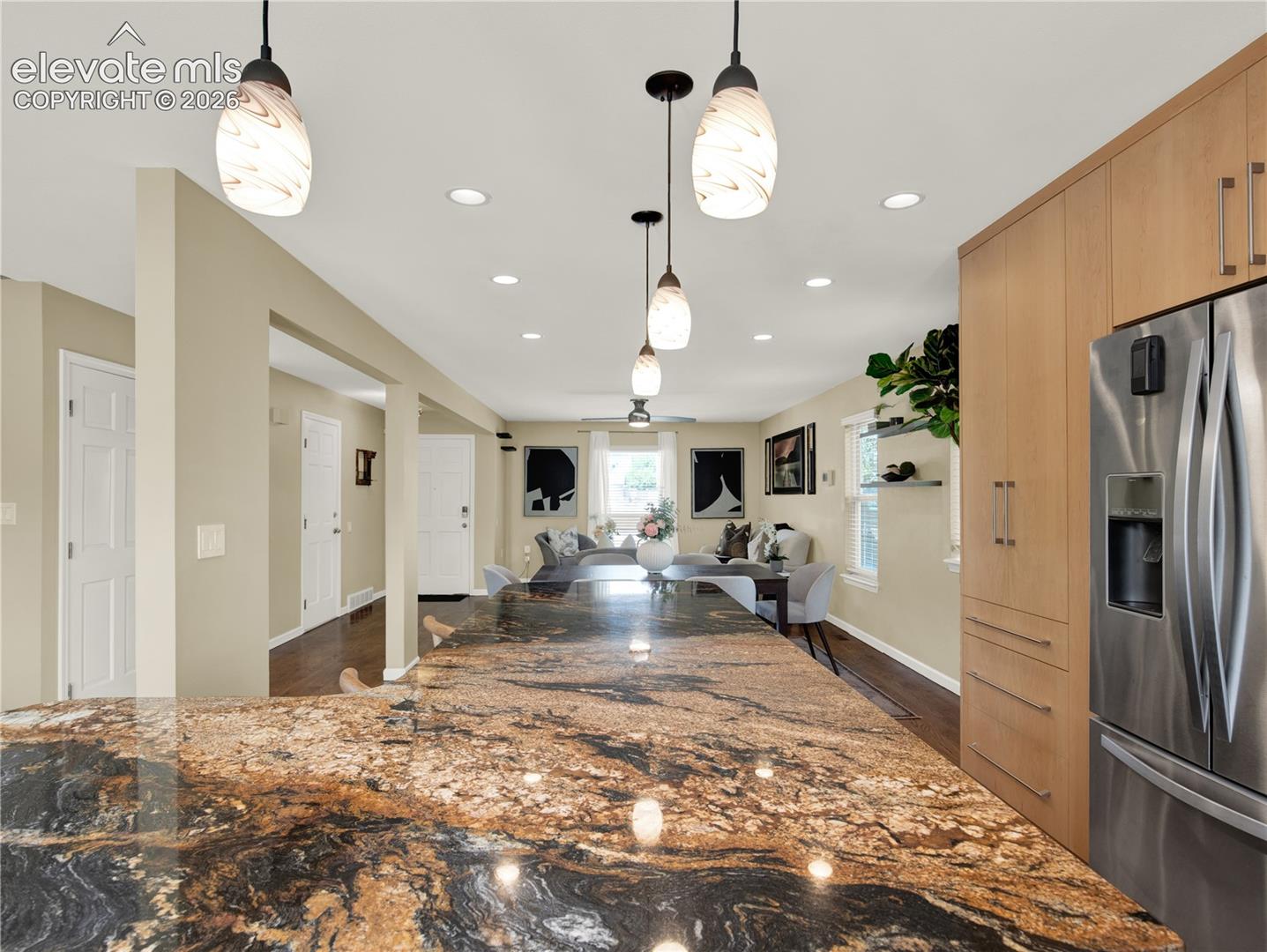 Kitchen featuring an expansive stone countertop island, flat-panel cabinetry, stainless steel refrigerator, recessed lighting, and glass pendant fixtures
