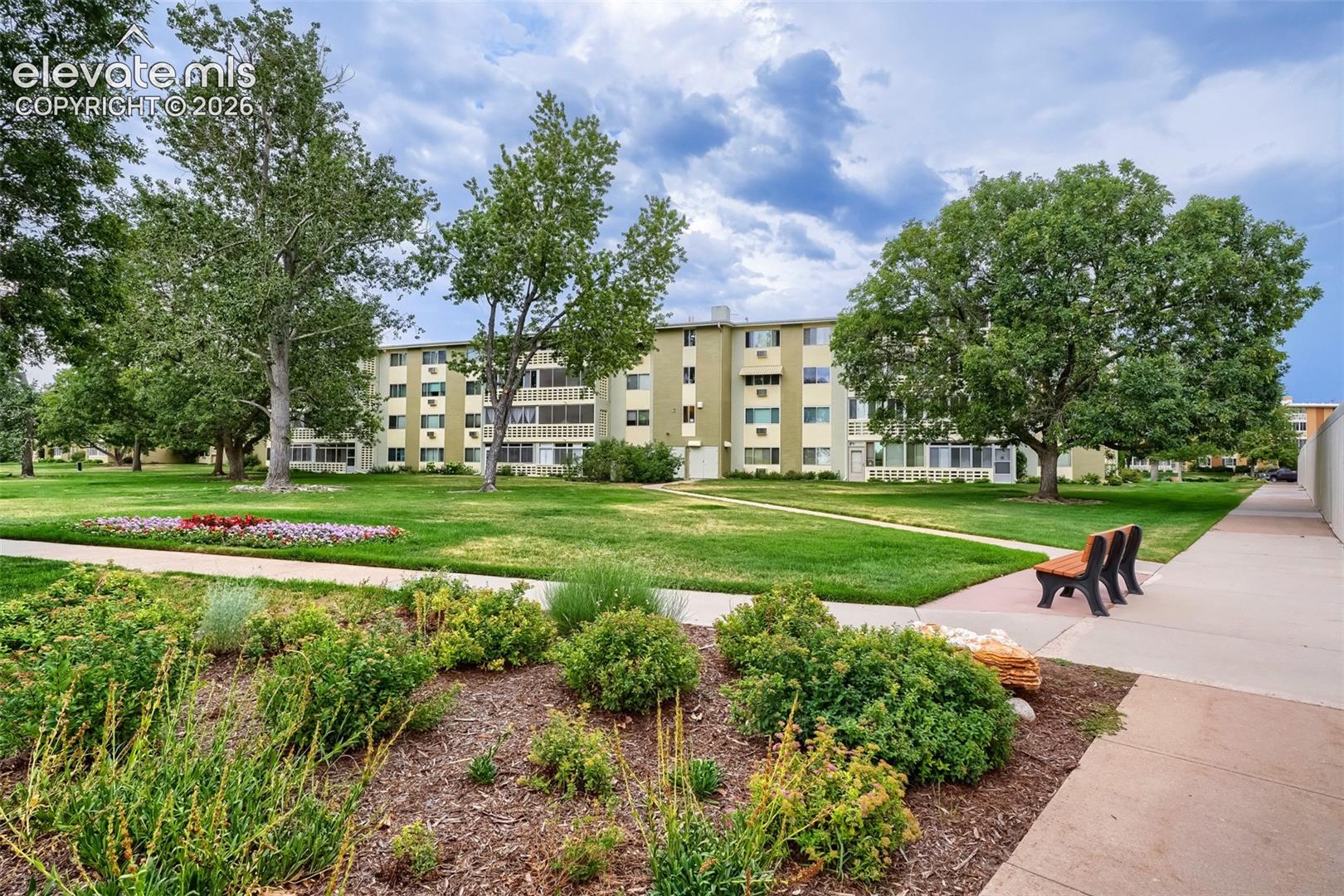 Expansive green space featuring mature trees, manicured lawns, and colorful flower beds