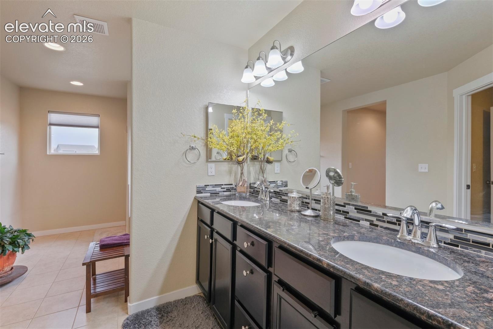 Upper Level: Dual vanity featuring dark cabinetry, stone countertop, and two undermount sinks with chrome fixtures