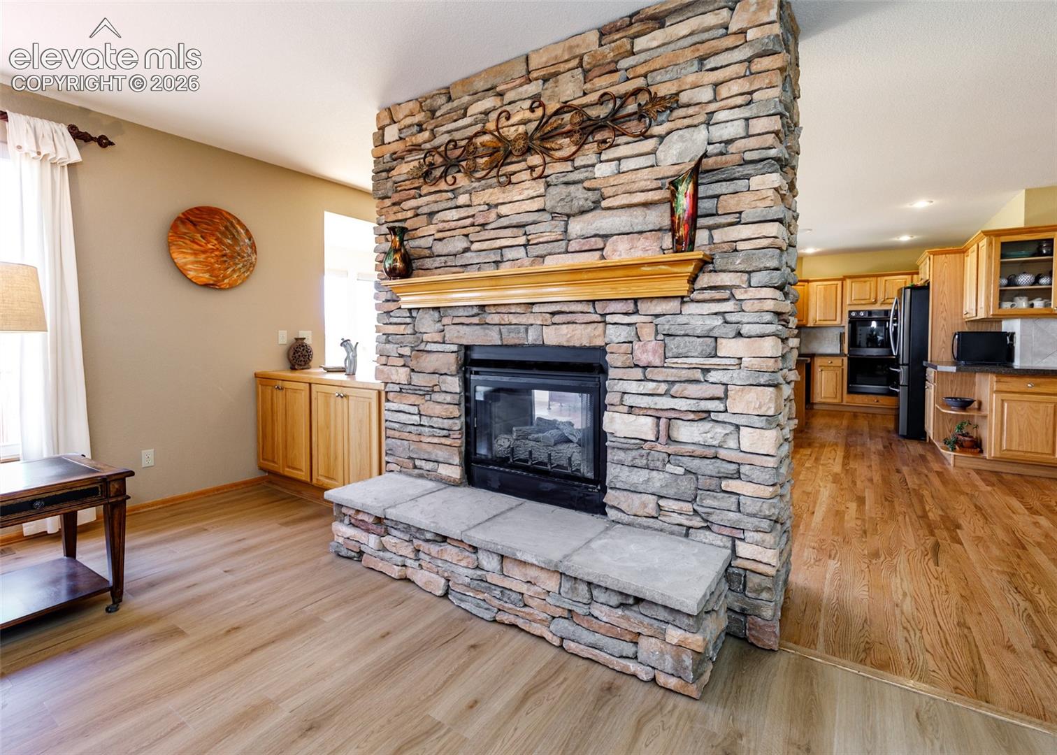 Stone-faced fireplace with a hearth and wood mantel