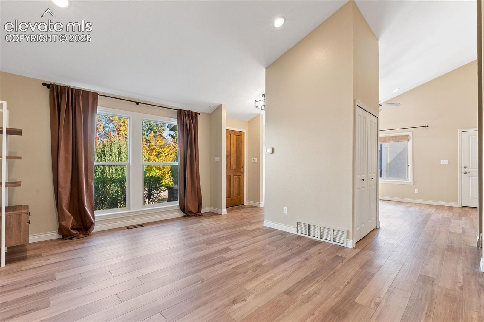 Vaulted ceilings, wood-finish flooring, recessed lighting, and large windows with natural illumination