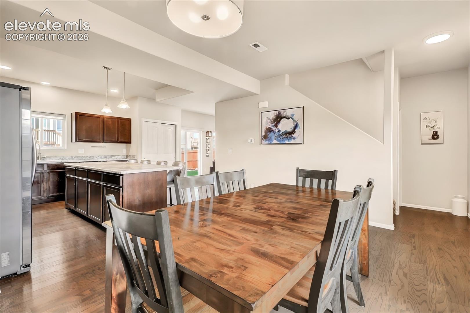 Kitchen featuring dark wood-finish cabinetry, an expansive center island with stone-finish countertops, wood-finish flooring, and recessed lighting