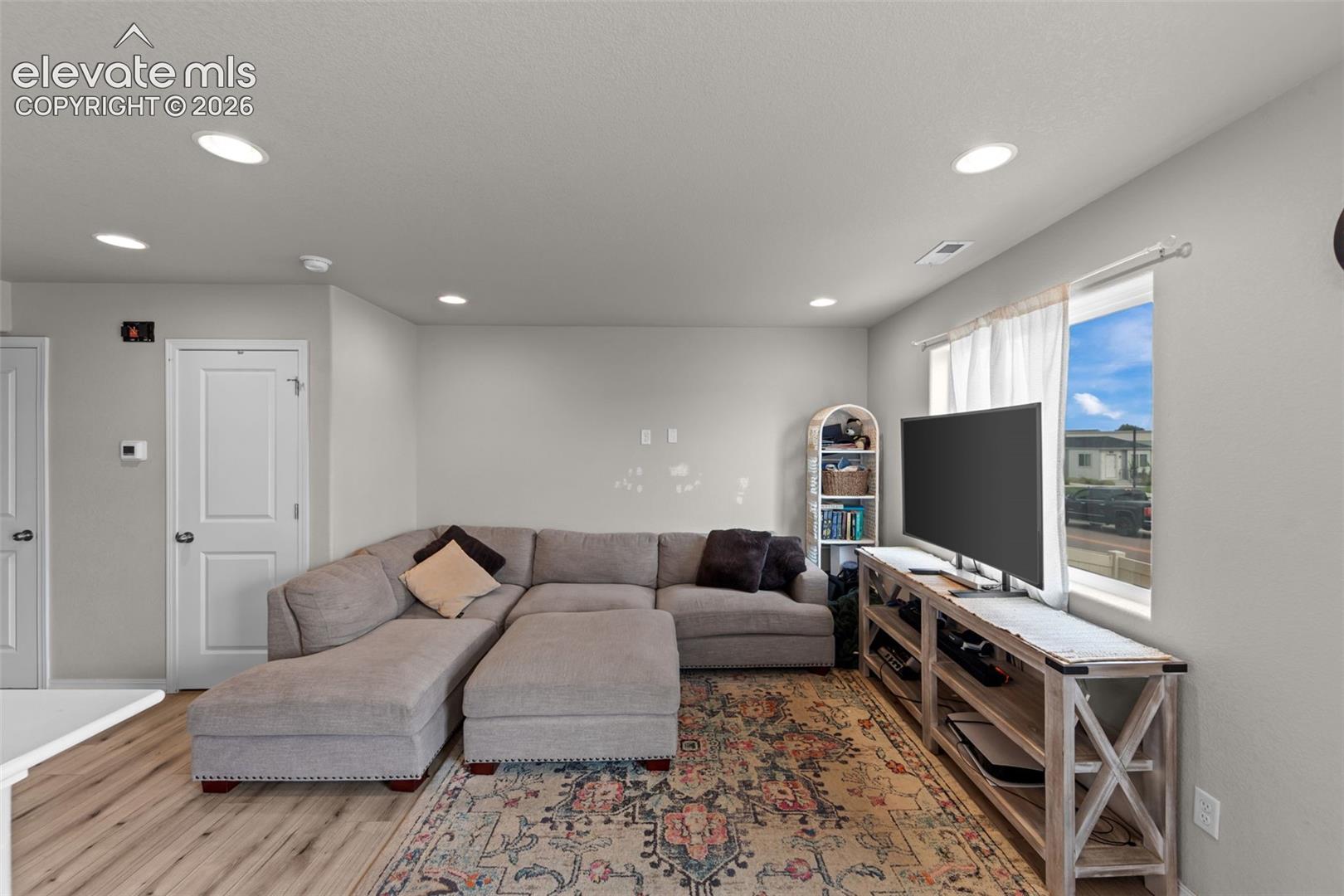 Recessed ceiling lighting, wood-finish flooring, white trim, and light gray wall color
